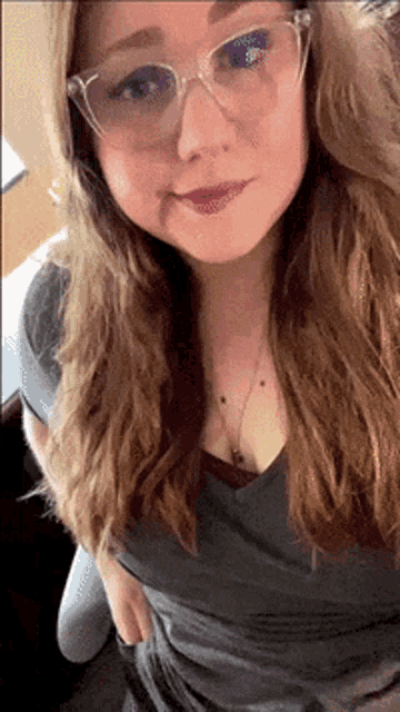 a woman wearing glasses and a gray shirt