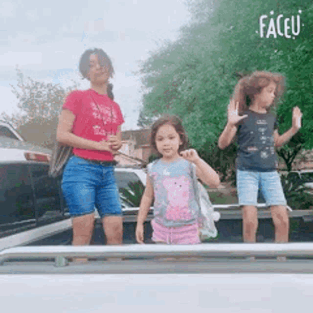 a woman and two little girls are standing on top of a truck .