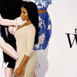 a woman in a white dress is standing in front of a wall with the letter v on it