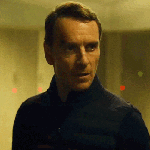 a man in a black jacket looks at the camera