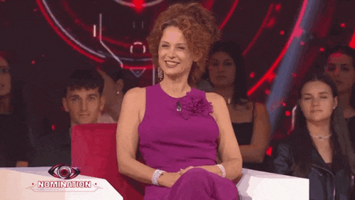 a woman in a purple dress is smiling in front of a nomination logo