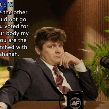 a man in a suit and tie sits at a table with a mug that says af