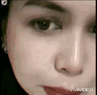 a close up of a woman 's face with a nose piercing .