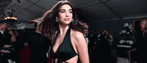 a woman in a black dress with a plunging neckline is walking on a red carpet
