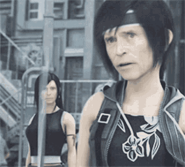 a woman in a black tank top with flowers on it stands next to another woman