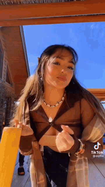 a woman in a brown crop top is standing on a deck .