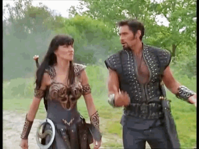a man and a woman are standing next to each other on a dirt road in a field .