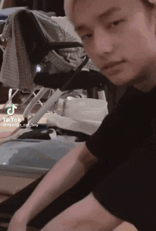 a young man in a black shirt is sitting on the floor in front of a projector screen .