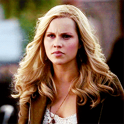 a woman with blonde hair and a necklace is looking at the camera
