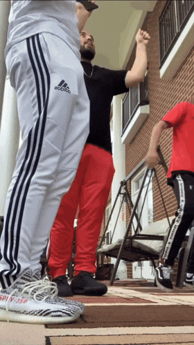 a man wearing red pants and white adidas sweatpants