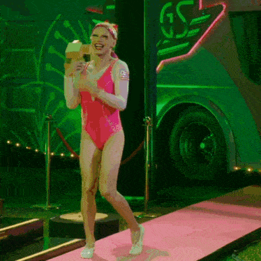 a woman in a pink swimsuit is walking down a pink runway