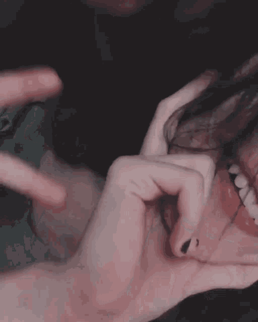 a close up of a person making a peace sign with their hand