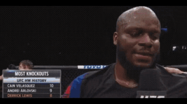a man is holding a microphone in front of a sign that says most knockouts on it