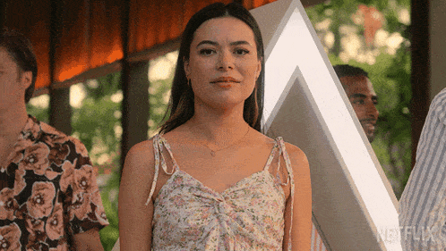 a woman in a floral dress stands in front of a sign that says netflix