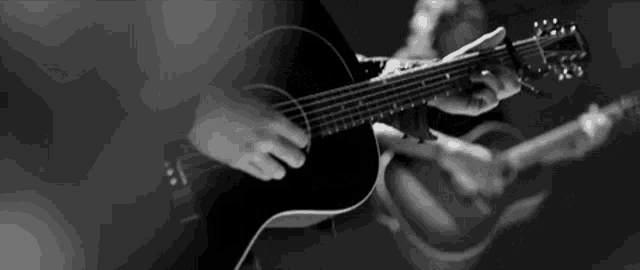 a black and white photo of a person playing a guitar