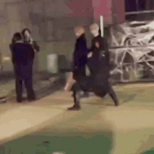 a blurry picture of a group of people standing next to each other on a sidewalk .