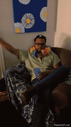 a man is sitting on a couch wearing a lei and holding a cup
