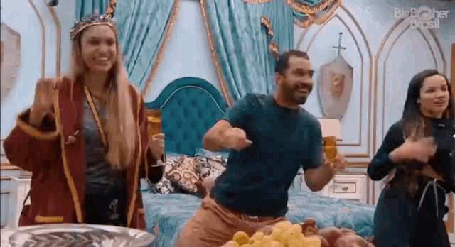 a group of people are dancing in a room with a bed and a bowl of grapes .