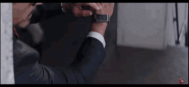 a man in a suit and tie is looking at his watch on his wrist .