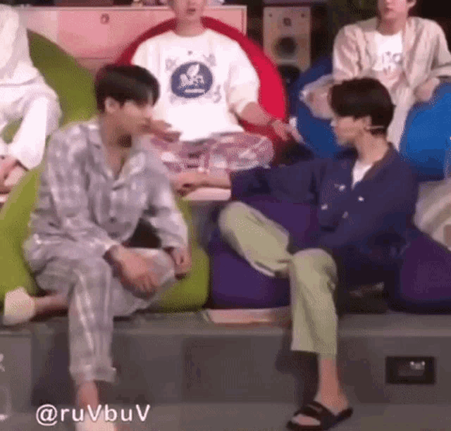 two men are sitting next to each other on bean bag chairs in a room .