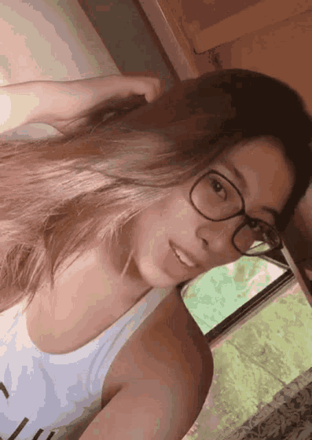 a woman wearing glasses and a white tank top with the letter c on the front