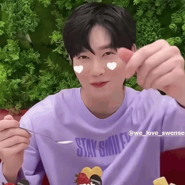 a man wearing a purple shirt that says stay smiley is holding a spoon