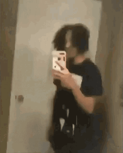 a blurry picture of a man taking a selfie in front of a mirror .