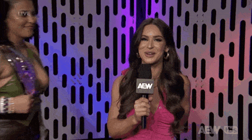 a woman in a pink dress is holding a microphone that says aew