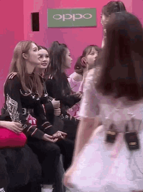 a group of girls are sitting in front of an oppo sign .