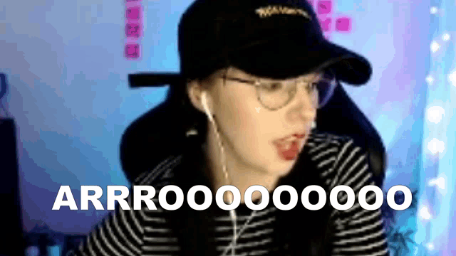 a woman wearing a hat and headphones is making a funny face while sitting in front of a computer .