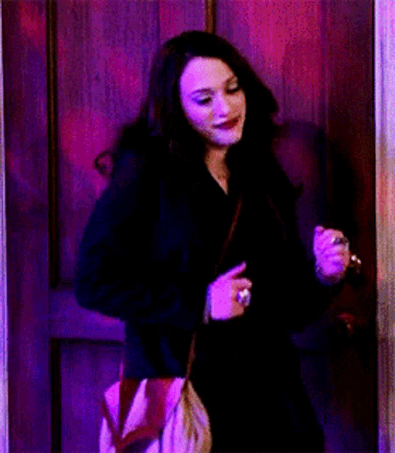 a woman in a black coat is standing in front of a door in a dark room