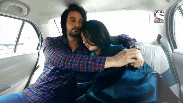 a man is hugging a woman in the back seat of a car with a sony television logo on the rear window
