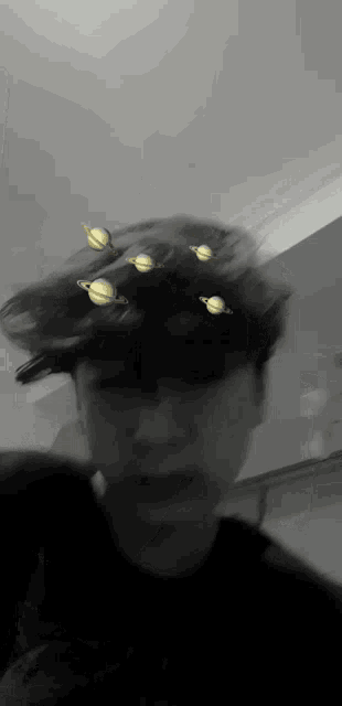 a blurry black and white photo of a person with planets on their head