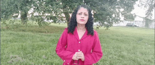 a woman in a pink shirt stands in a field