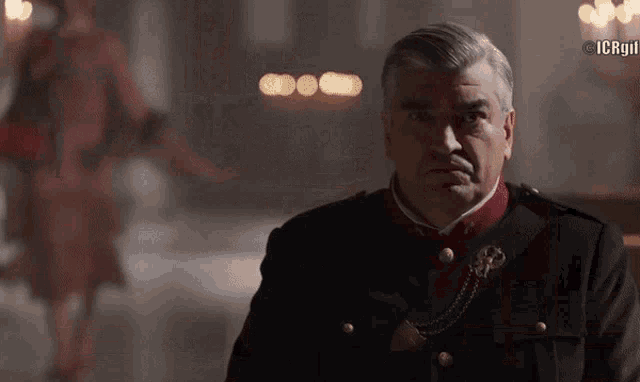 a man in a military uniform is standing in a dark room with a blurred background that says ' icp '