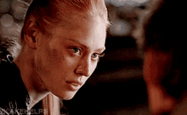 a close up of a woman 's face with a man 's face in the background .