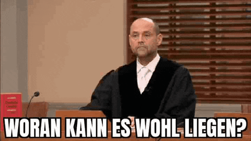 a man in a judge 's robe is sitting at a podium with a microphone in front of him .