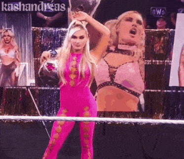 a woman in a pink outfit is standing in a wrestling ring with a sign that says kashiandras on it