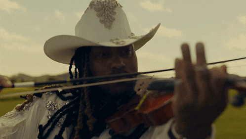 a man wearing a white cowboy hat is playing a violin
