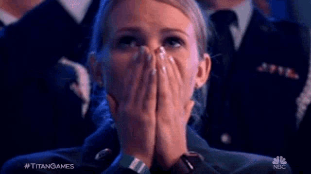 a woman is covering her mouth with her hands while watching a game .