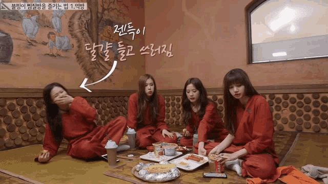 a group of girls are sitting on the floor eating food in a room with chinese writing on the wall