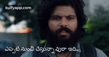 a man with a beard is looking at the camera with a foreign language written on the bottom .
