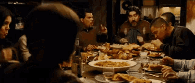 a group of people are sitting around a table with plates of food on it