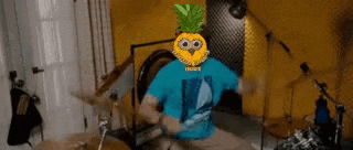 a man with a pineapple on his head is playing the drums