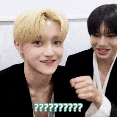 a man with blonde hair is smiling next to another man with black hair and the words " ?? " written on the bottom