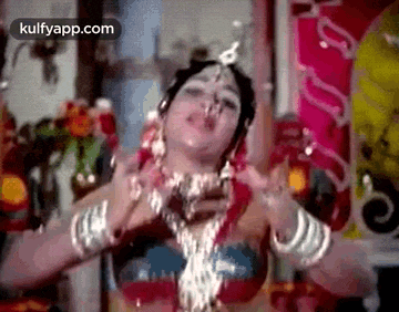 a woman in a red top and white jewelry is dancing .