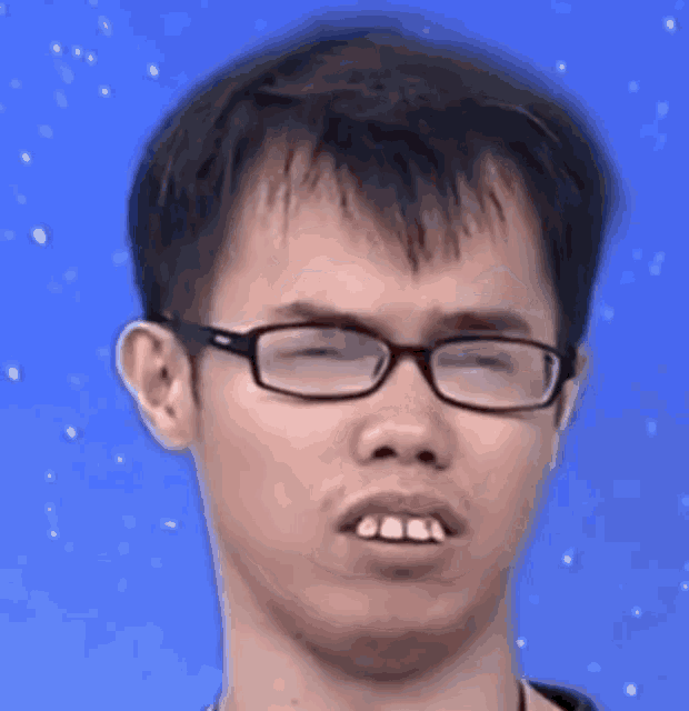 a young man wearing glasses is making a funny face with his eyes closed .