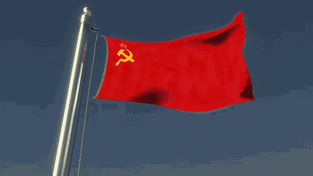a red flag with a hammer and sickle on it is waving in the wind