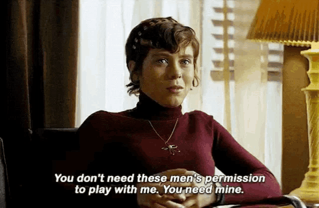 a woman in a red sweater is sitting in a chair and talking to someone .