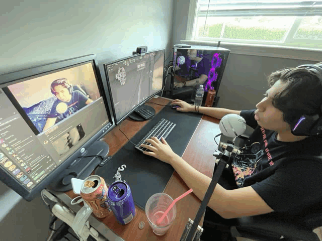 a man sitting at a desk with two monitors and a can of monster energy drink